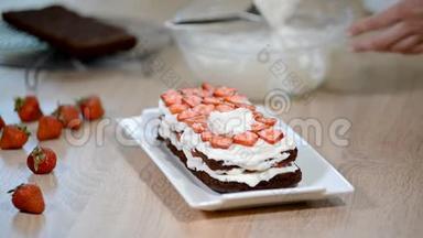 女人的手在草莓蛋糕上放生奶油。